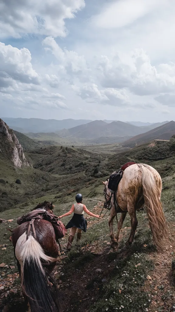 Jinete guiando caballos por la montaña